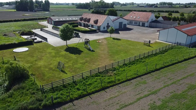 Schommel met klimtoren en glijbaan voor de kinderen met op de achtergrond vakantiehuis De Finesse